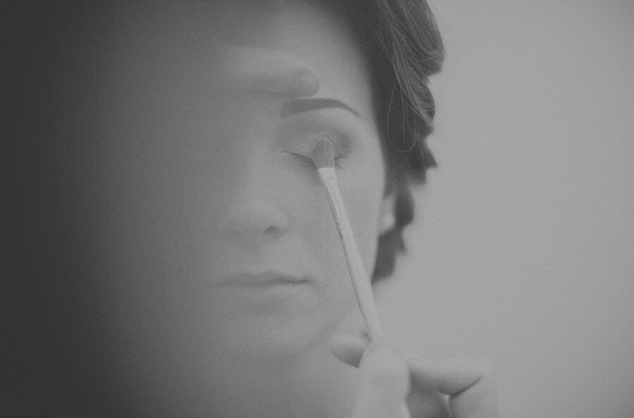 The make up artist applies make up to the brides eye