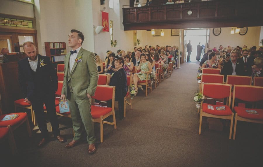 The groom and the best man stand nervously as they wait for the bride to enter the church