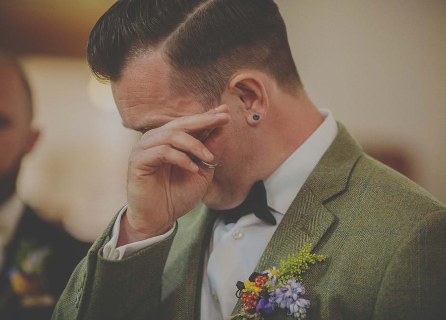 The groom wipes a tear from his eye