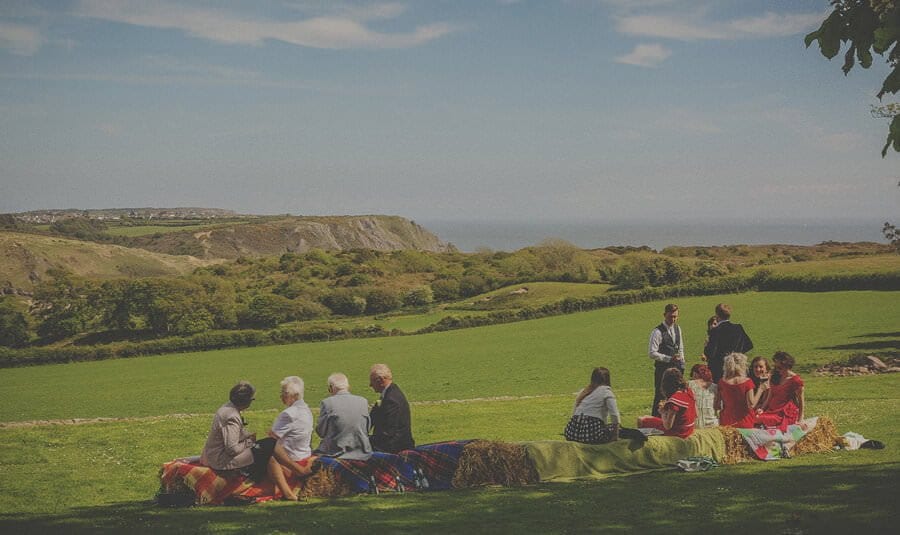 Wedding guests sit on hay bails in the garden of Penmaen house
