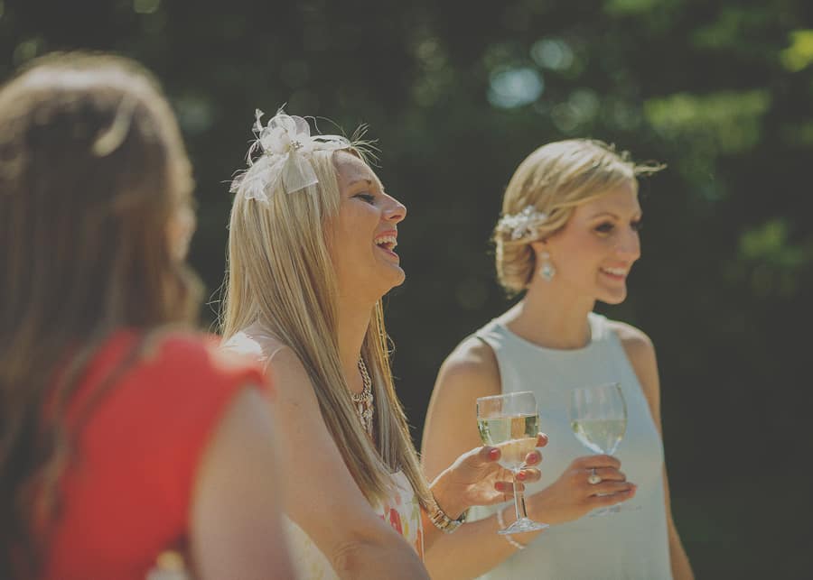 A lady holding a champagne glass laughs with friends