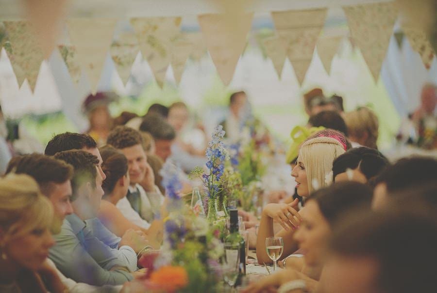 Wedding guests talk as they sit in the marquee