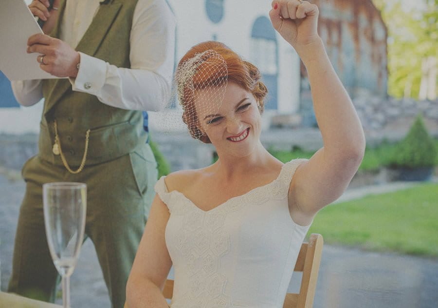 The bride raises her arm and smiles
