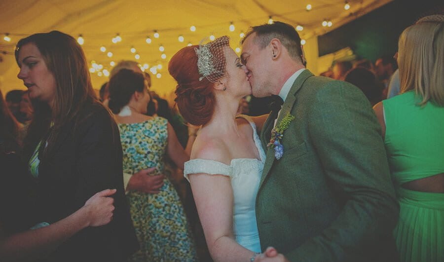 The bride and groom kiss each other on the dancefloor