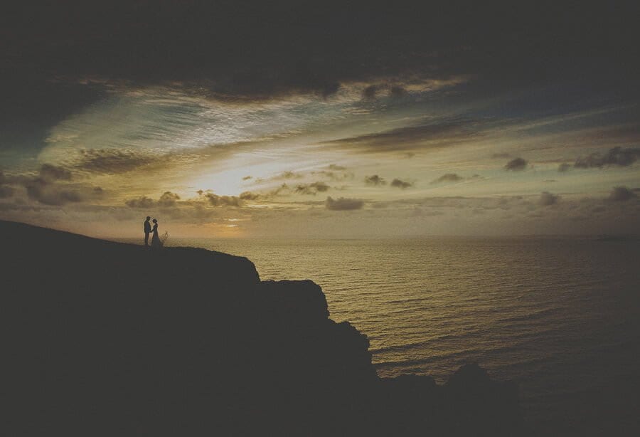 The bride and groom watch the sun go down at Rhosilli beach