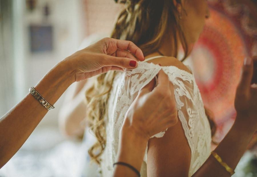 The back of the brides dress is straightened by the bridesmaid
