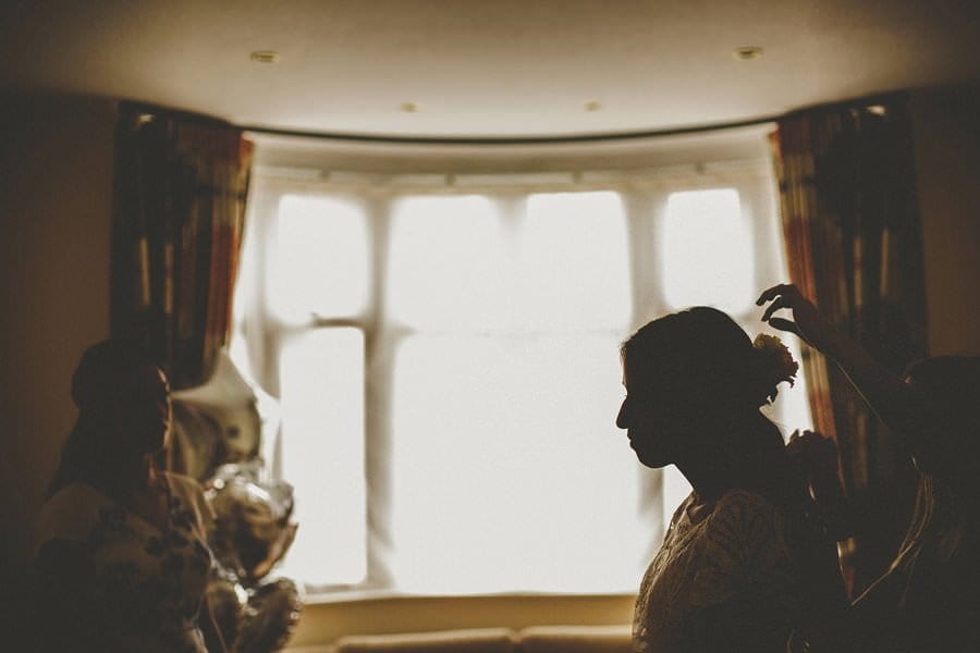 The hairdresser places a flower at the back of the brides hair