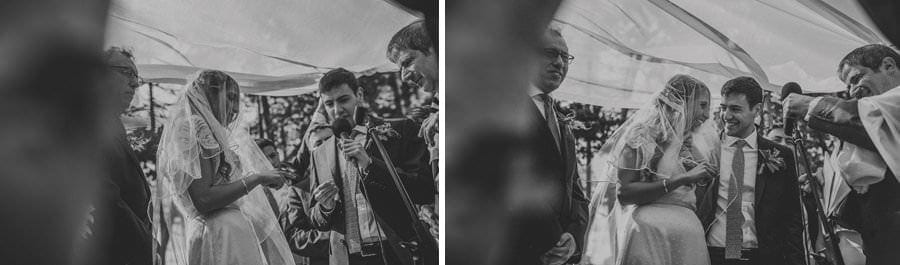 The bride and groom stand under the chuppah together for the outdoor ceremony