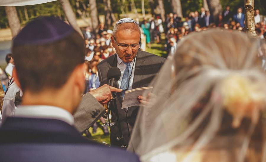 A man holds a microphone in front of the bride and groom