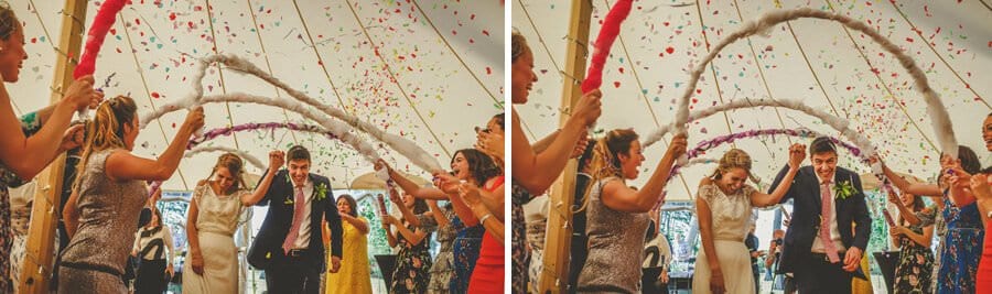 The bride and groom hold hands and walk into the marquee