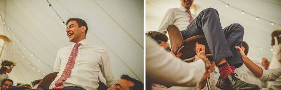 The groom is lifted into the air by the ushers in the marquee