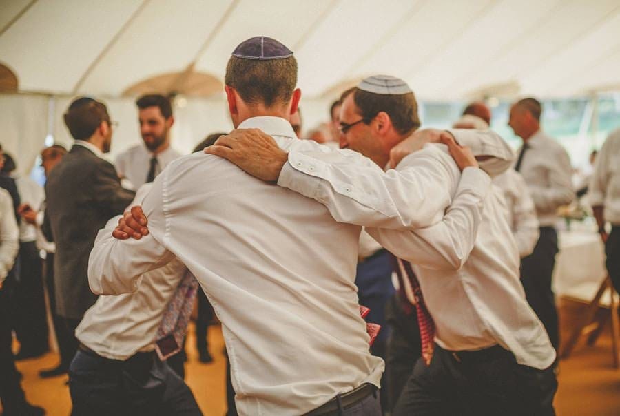 Wedding guests hold each other and dance in the marquee