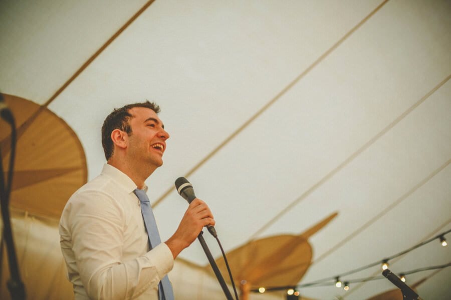 A man speaks to the wedding guests in the marquee