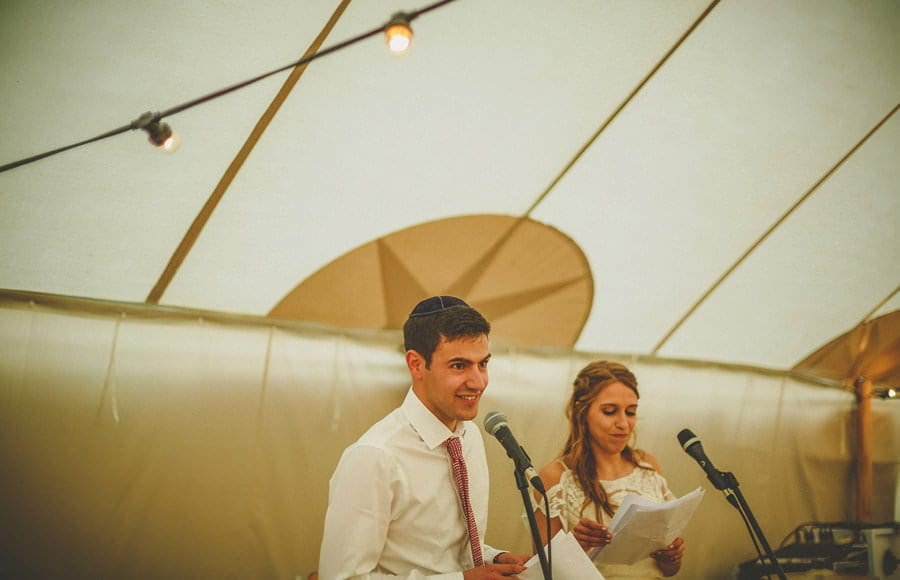 The groom stands in the marquee with his bride and delivers his speech to the wedding guests