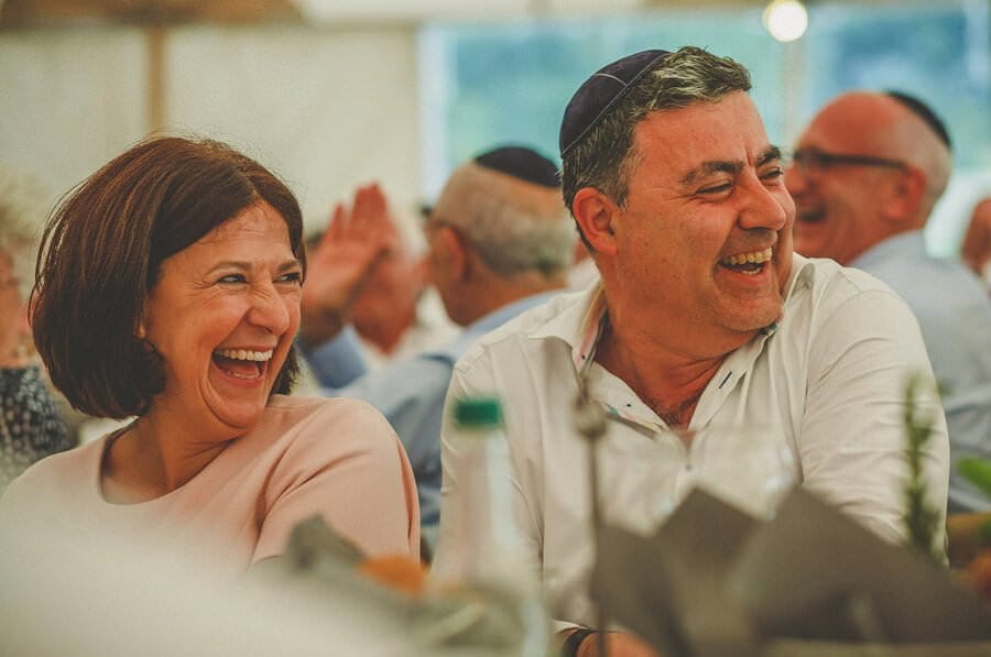 The grooms mother and father laugh at their sons speech in the marquee