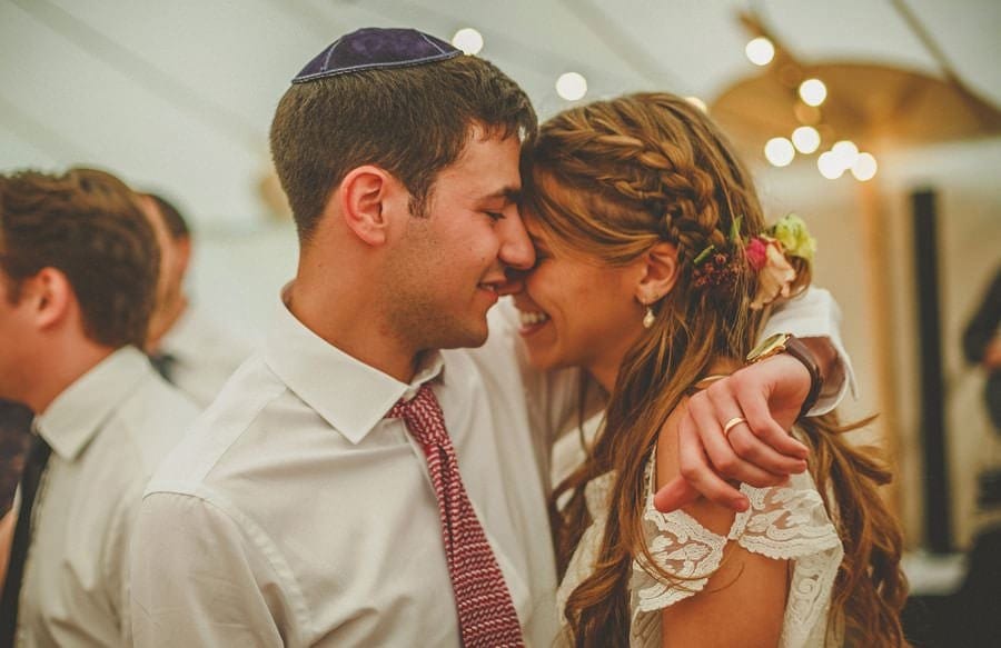 The groom holds his wife and puts his face next to hers in the marquee