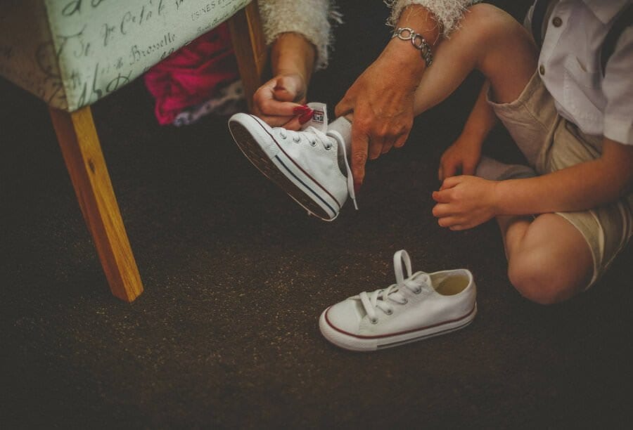 A child puts on his wedding shoes with help from his grandmother