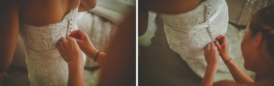 The bride has help putting on her dress