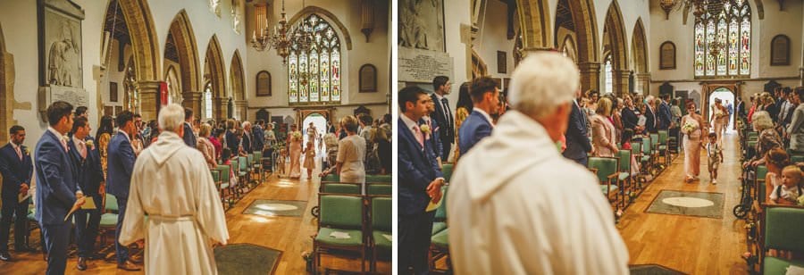 The bridesmaids and flower girls walk down the aisle of the church at St Michaels all angels