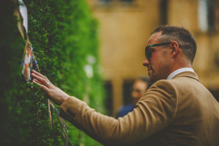 A wedding guest looks at photographs of the bride and groom in the garden