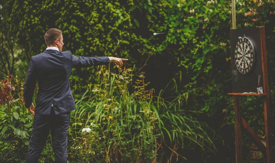 A man throws a dart at a board in the garden