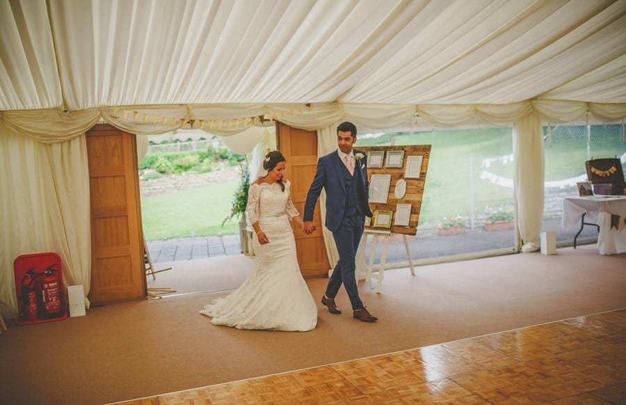 The bride and groom enter the marquee in the old bridge garden