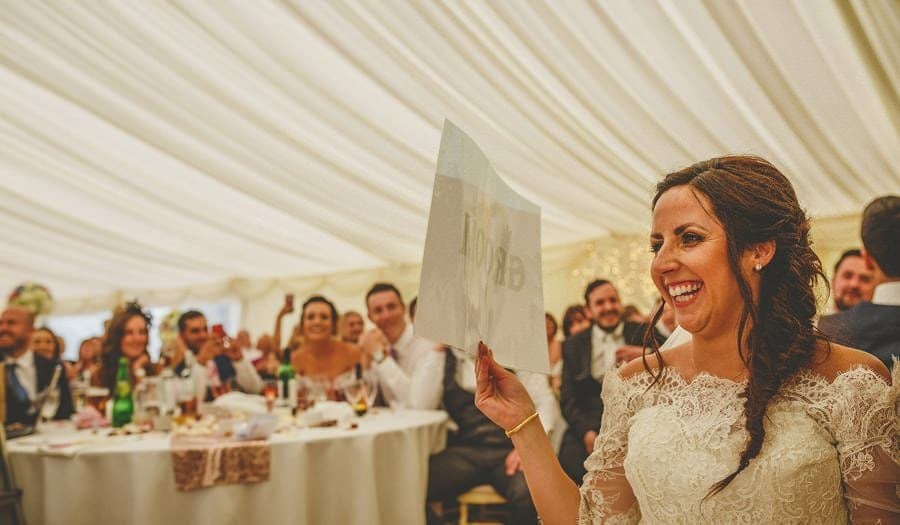 The bride lifts up a piece of paper and laughs