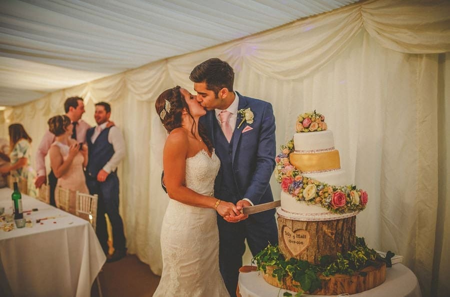 The bride and groom cut their wedding cake in the marquee at the old bridge petherton