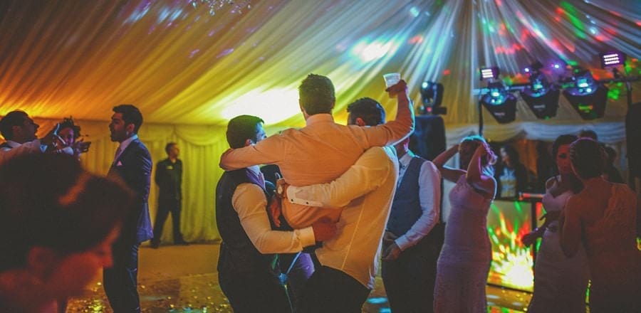Ushers pick up the groom as he raises his glass in the air