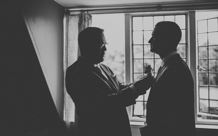 The best man places a flower on the lapel of the grooms suit