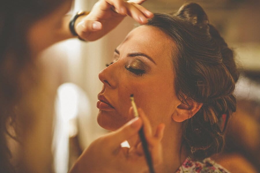 The make up artist applies eye liner to the brides eyelashes