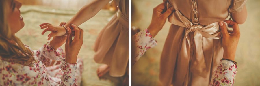 A bridesmaid fastens the ribbons to the back of the flowergirls dress
