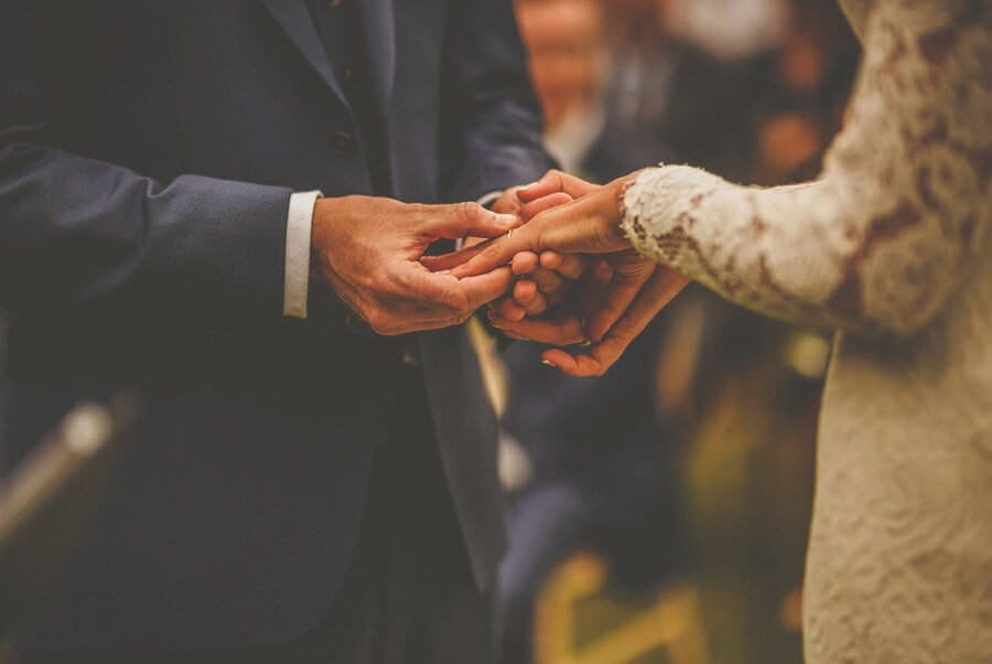 The groom places the wedding ring on the finger of the bride during the outdoor ceremony