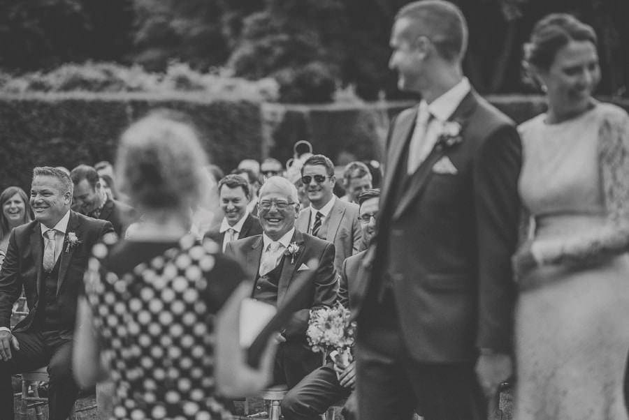 The grooms father and best man laugh during the outdoor wedding ceremony