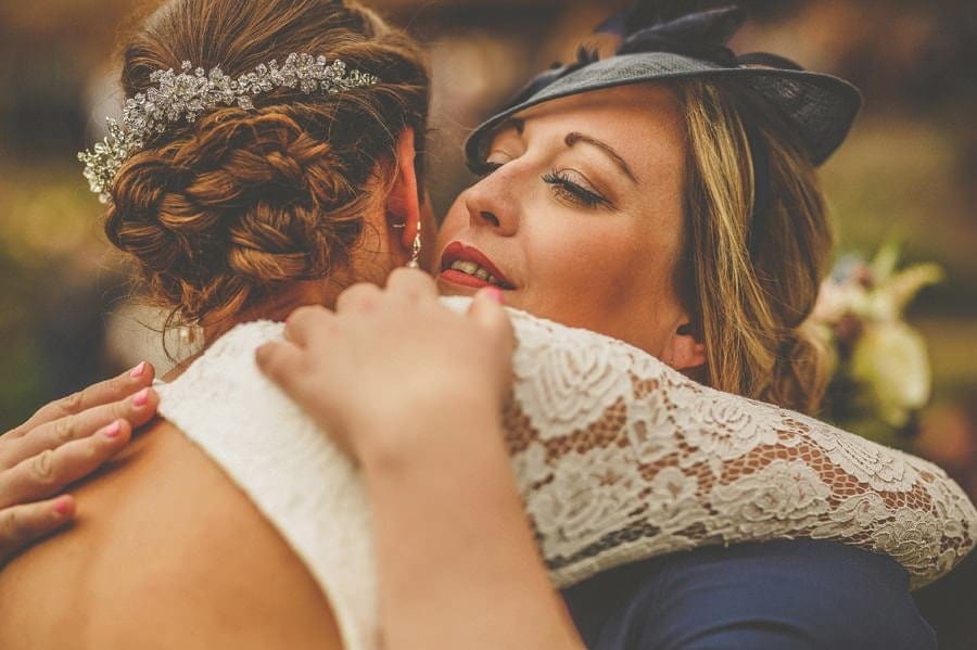 A wedding guest embraces the bride at the end of the outdoor wedding ceremony