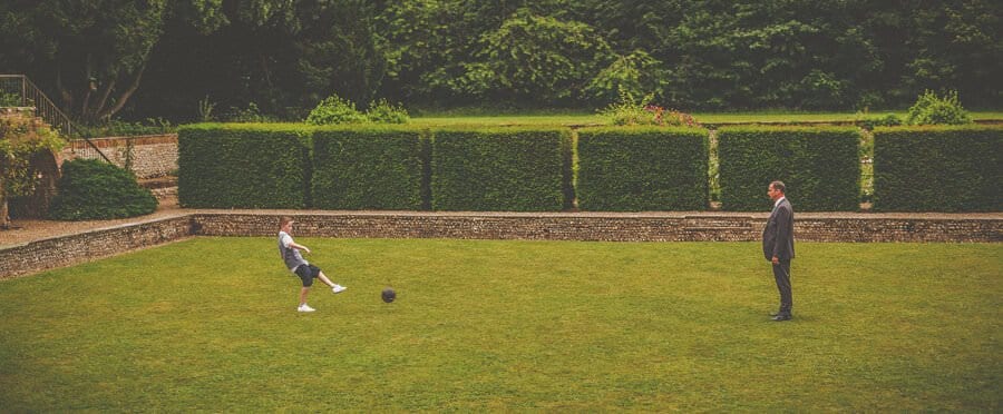 A boy kicks a football towards his father on the lawn at Voewood