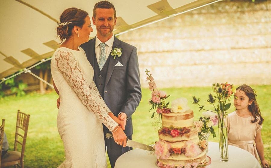The bride and groom cut the cake in the marquee at Voewood