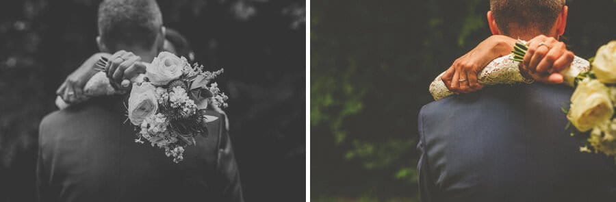 The bride holds her flowers and puts her arms around the groom in the gardens at Voewood