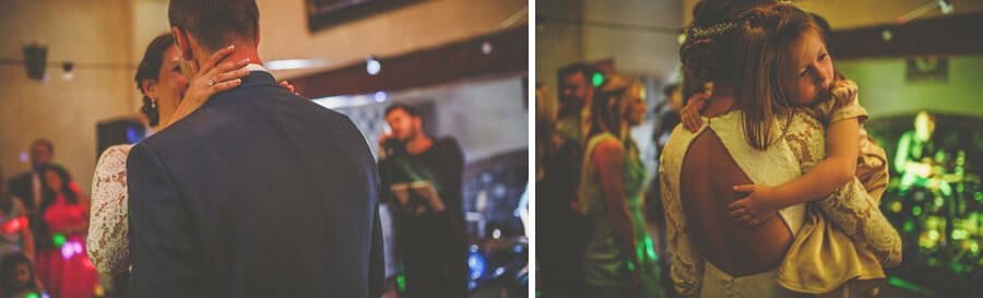 The bride holds a flowergirl in her arms on the dancefloor at Voewood