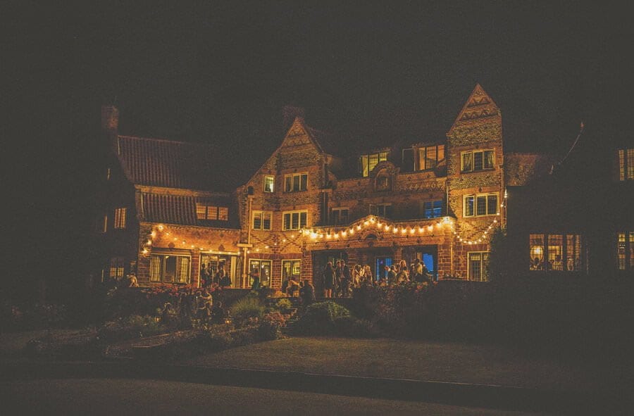 Wedding guests stand outside late in the evening at Voewood