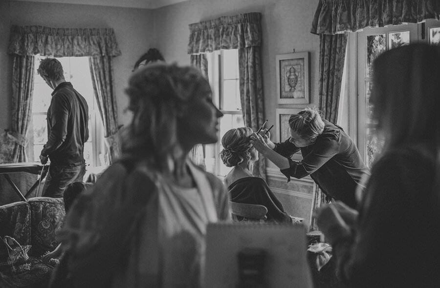 The make up artist applies make up to the bride