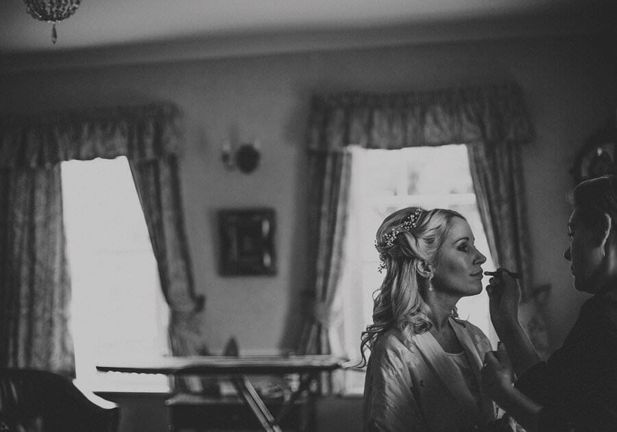 The make up artist applies lipstick to the brides lips