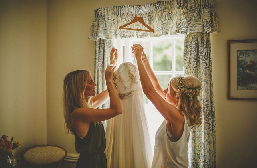 The bride and her friend take the wedding dress off the clothes hanger