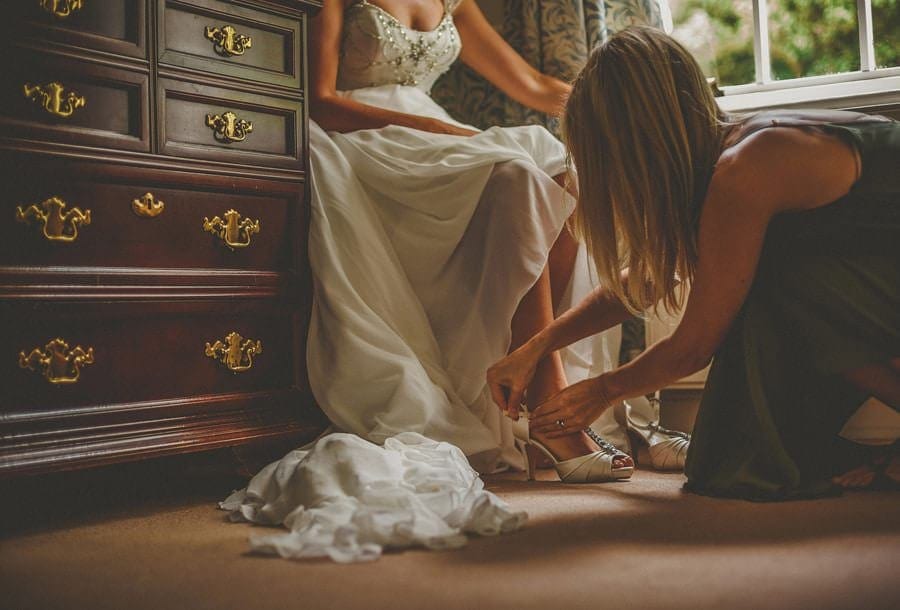 A friend puts on the shoes for the bride