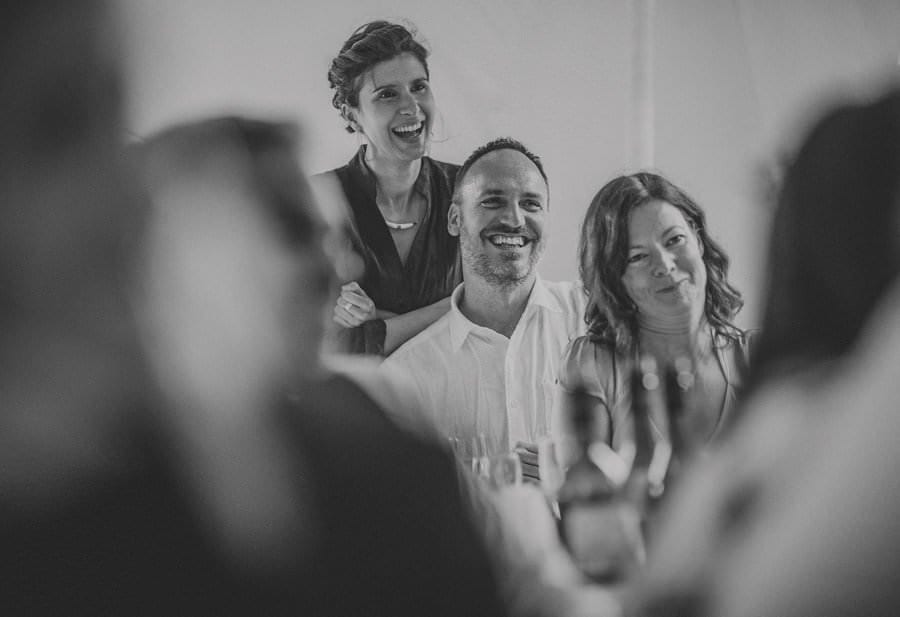 Wedding guests laugh at photographs of the bride and groom