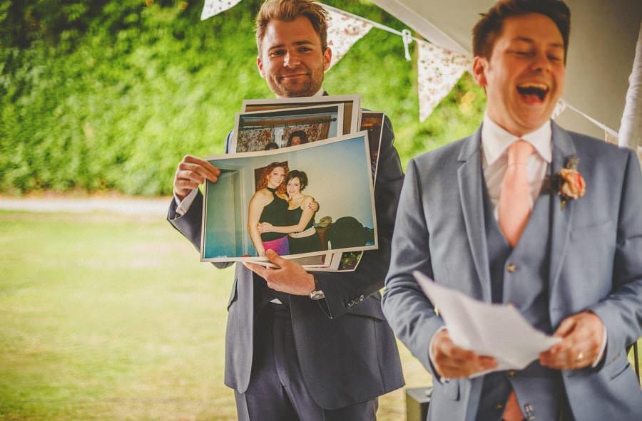 A photograph of the bride makes the groom laugh during the speeches