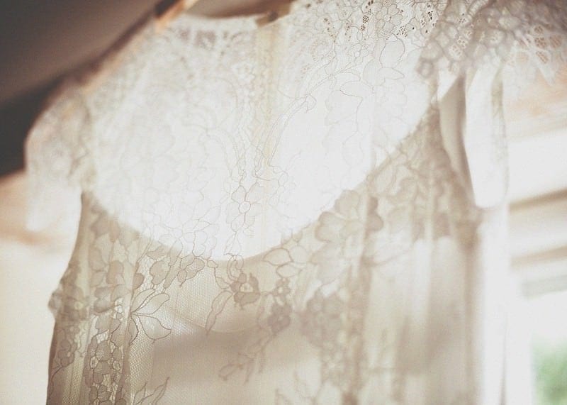 The brides dress hangs on the curtain rail