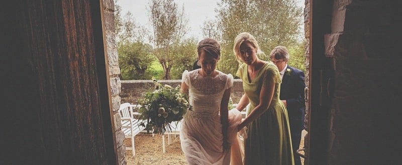 The bride, her father and a bridesmaid enter the doorway at Almonry Barn