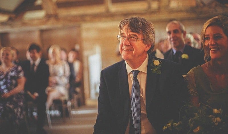 The brides father smiles during the wedding ceremony at Almonry Barn