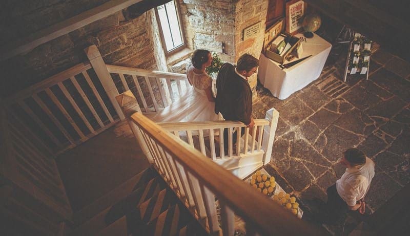 The bride and groom walk down the staircase at Almonry Barn